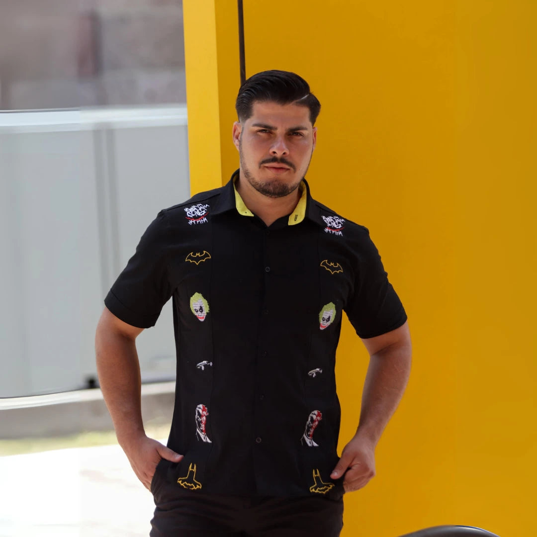 Modelo masculino luciendo guayabera negra de manga corta en 100% algodón, con bordados temáticos inspirados en iconos de la cultura urbana y justicieros nocturnos, diseño exclusivo de Guayaberas LeMaan.